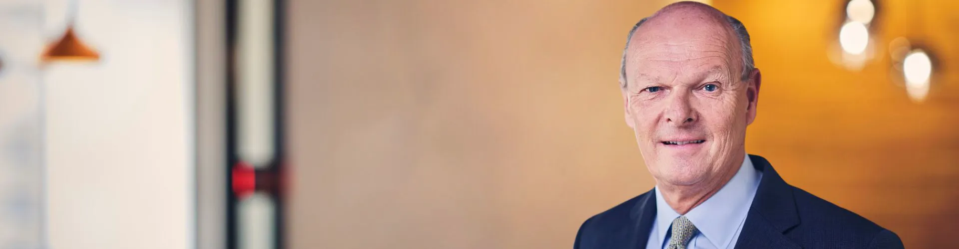 Man in a suit smiling in an indoor setting.