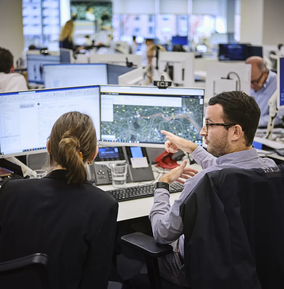 man at his desk explaining something on the screen to a female colleague