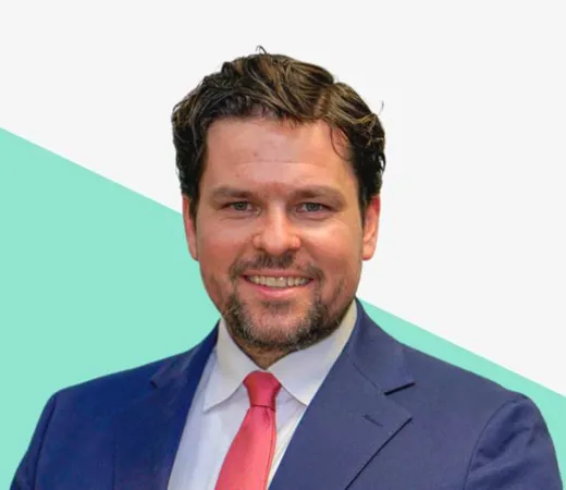 Man in a suit smiling against a light background.