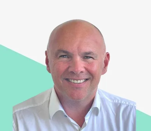 Smiling man in a white shirt against a light background.