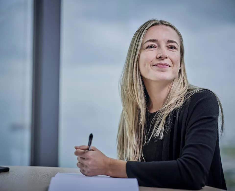 woman sitting at table with notepad and pen, looking over
