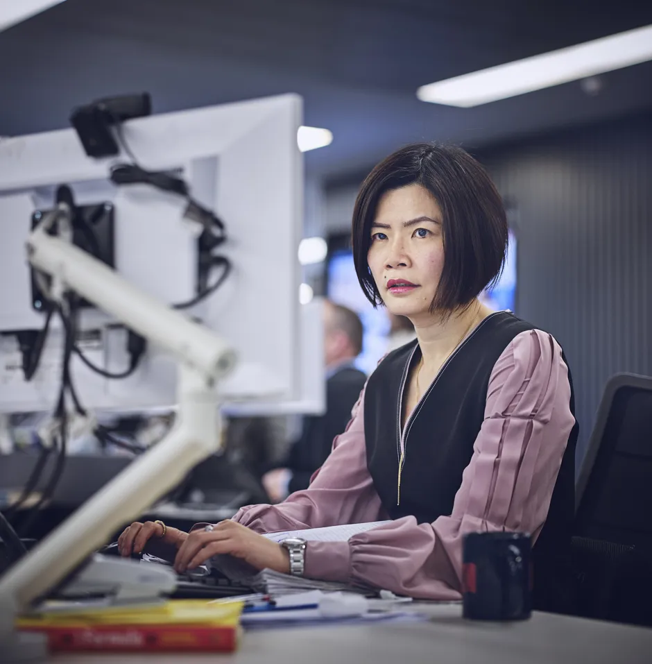 Woman working at a desk with computers.
