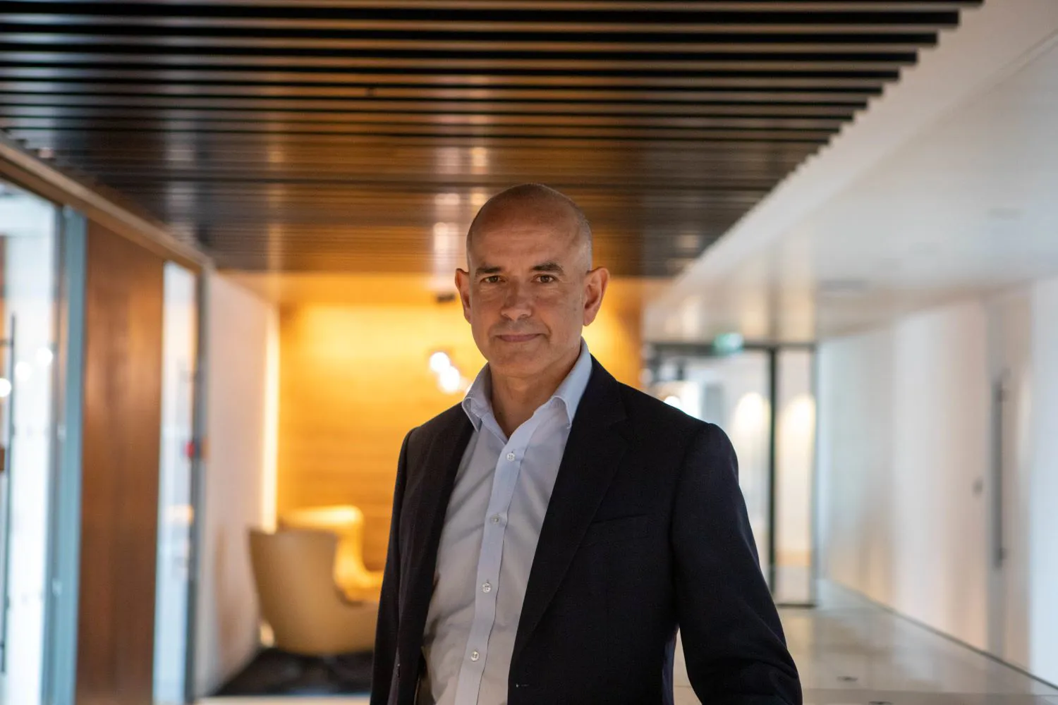 Man in a suit standing in a modern hallway.