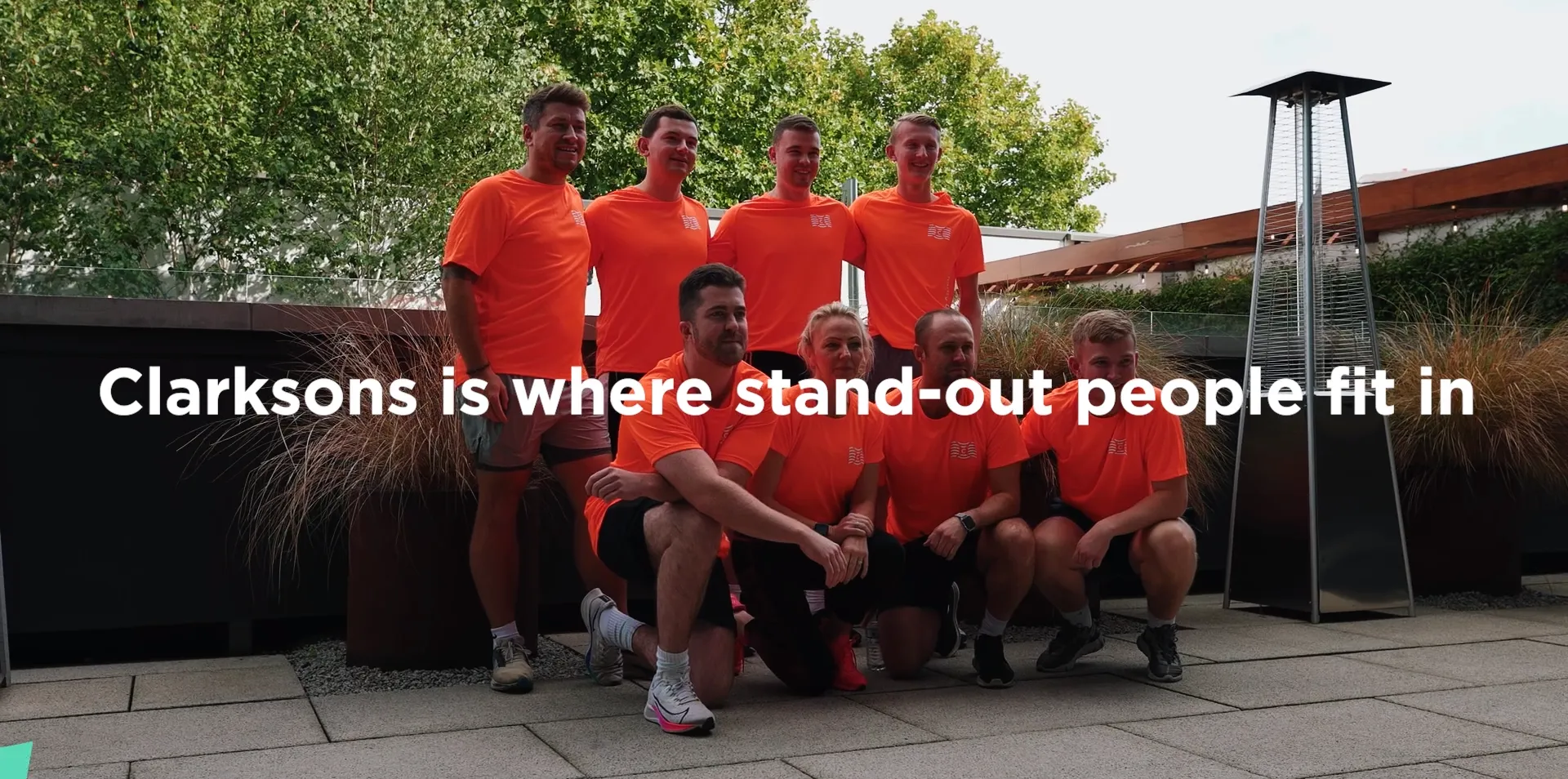 Group in orange shirts posing outdoors.