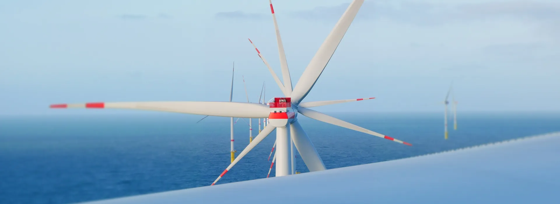 Close-up of a wind turbine with white blades and red markings against the ocean and sky.