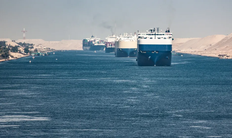 Several large cargo ships on a waterway.