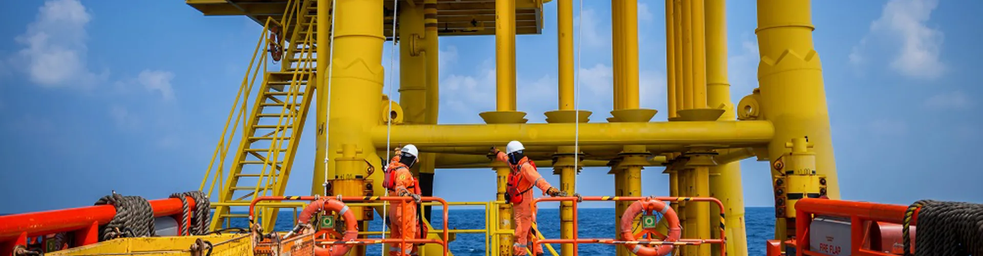 Two workers on a yellow offshore platform.