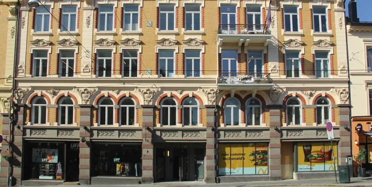 Historical building with yellow brick, ornate details, arched windows, and storefronts below.