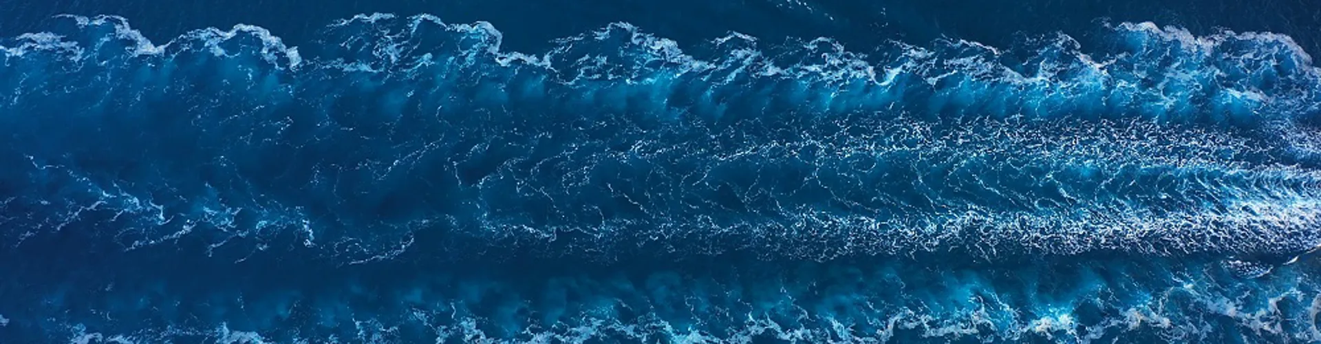Aerial view of ocean waves and wake trails.