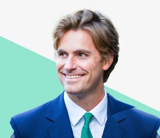Smiling man in a suit with a green tie.