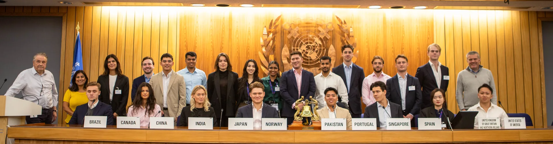 Group photo at a conference with flags and signage.