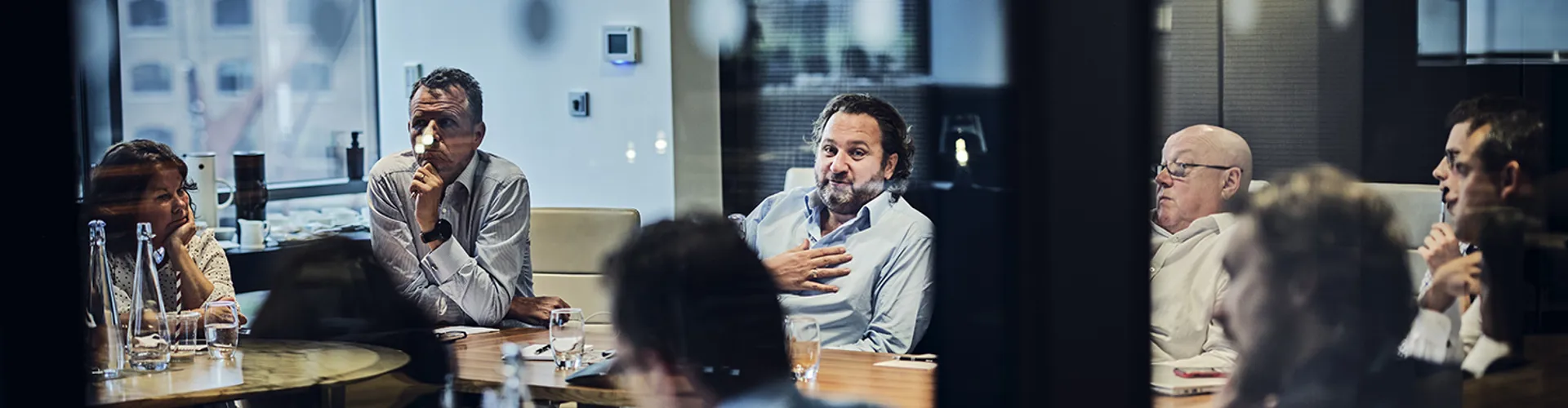 looking through a meeting room window at seniour employees