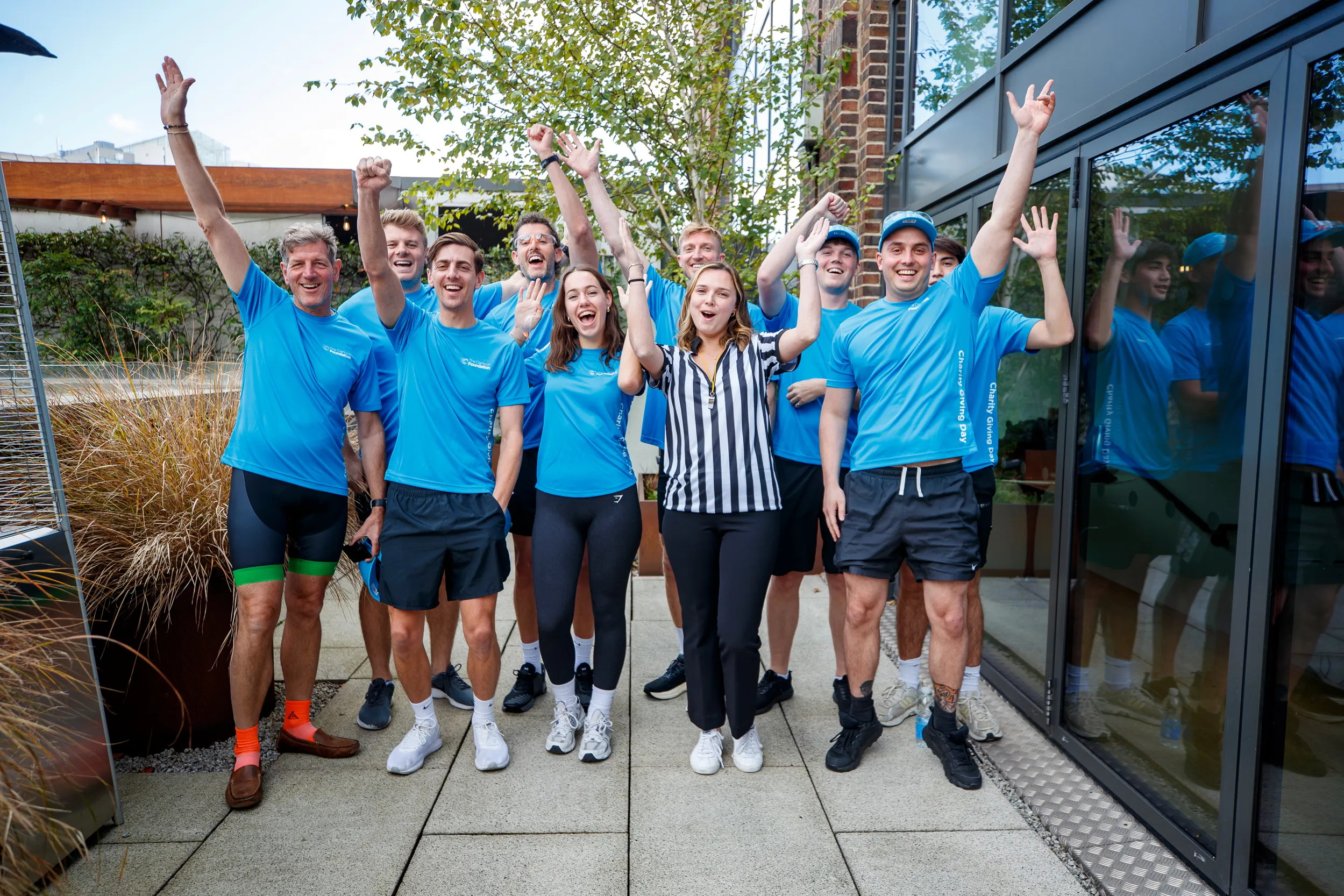 Group of people celebrating outdoors, raising hands.