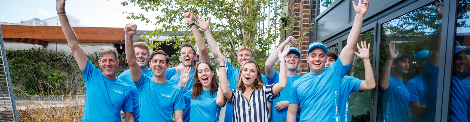Group of people celebrating outdoors, raising hands.