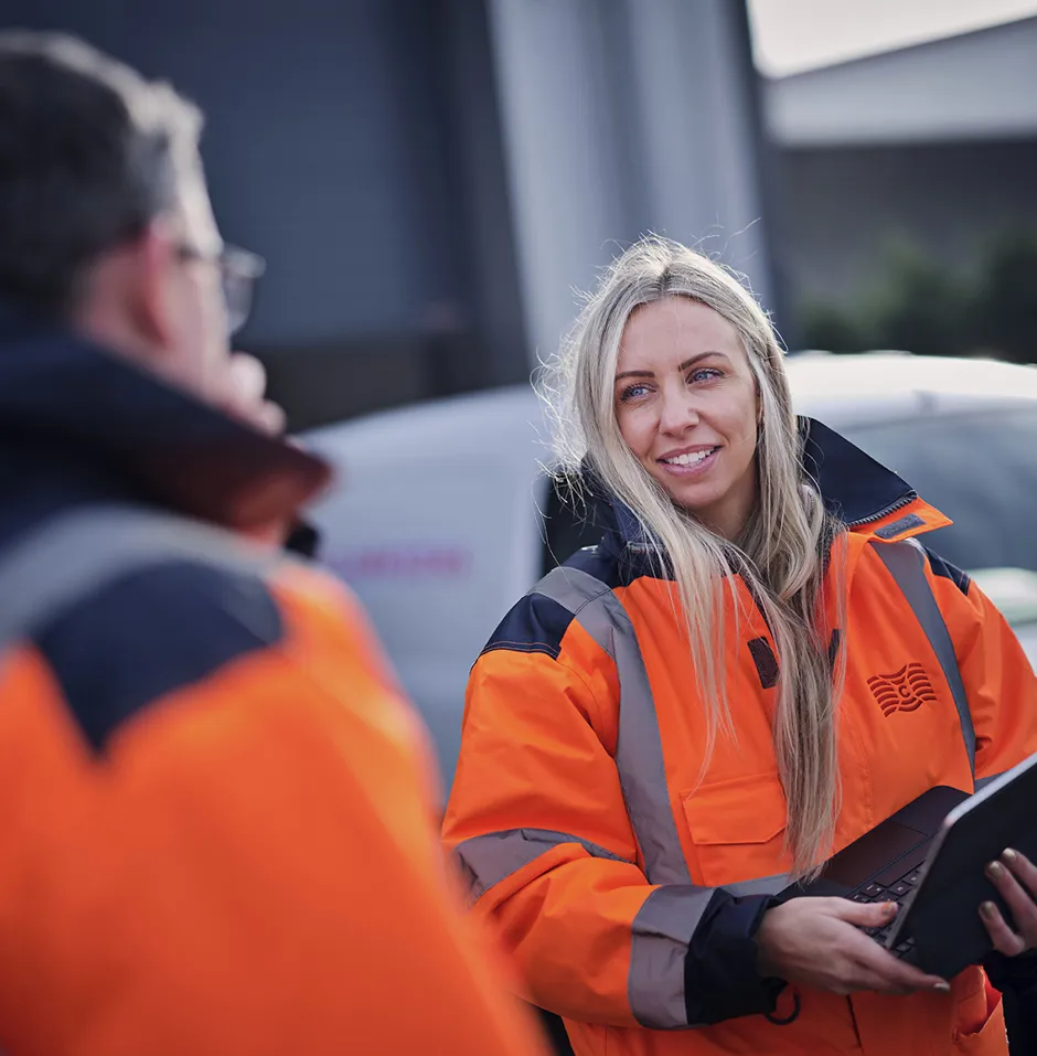 DOEL female employee in high vis jacket talking to colleagues
