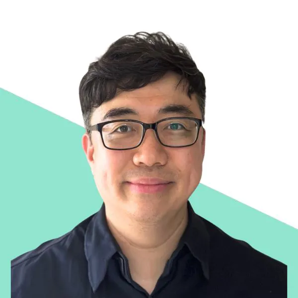 Man with glasses smiling on a two-tone background.