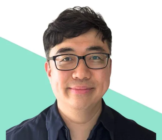 Man with glasses smiling on a two-tone background.