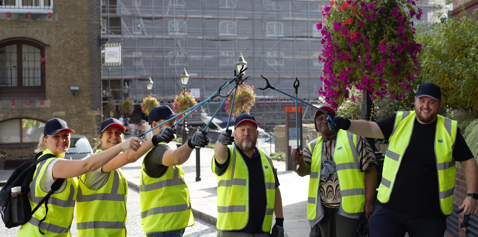 group of DOEL employees in hi vis jackets with litter pickers