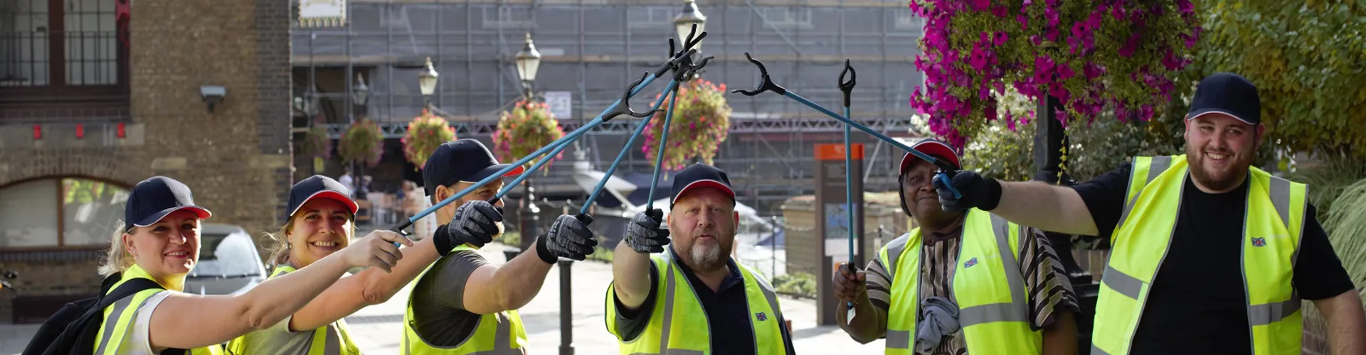 group of DOEL employees in hi vis jackets with litter pickers