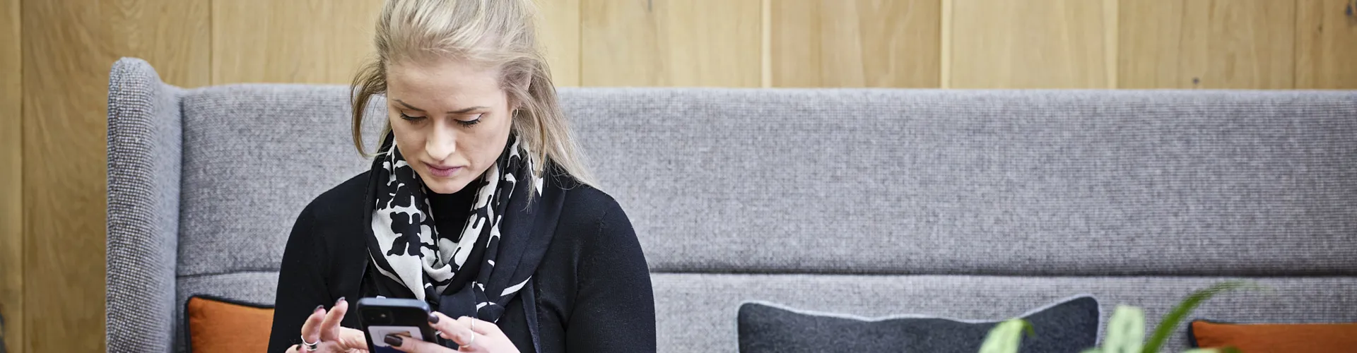 woman sitting on chair, looking down at her phone