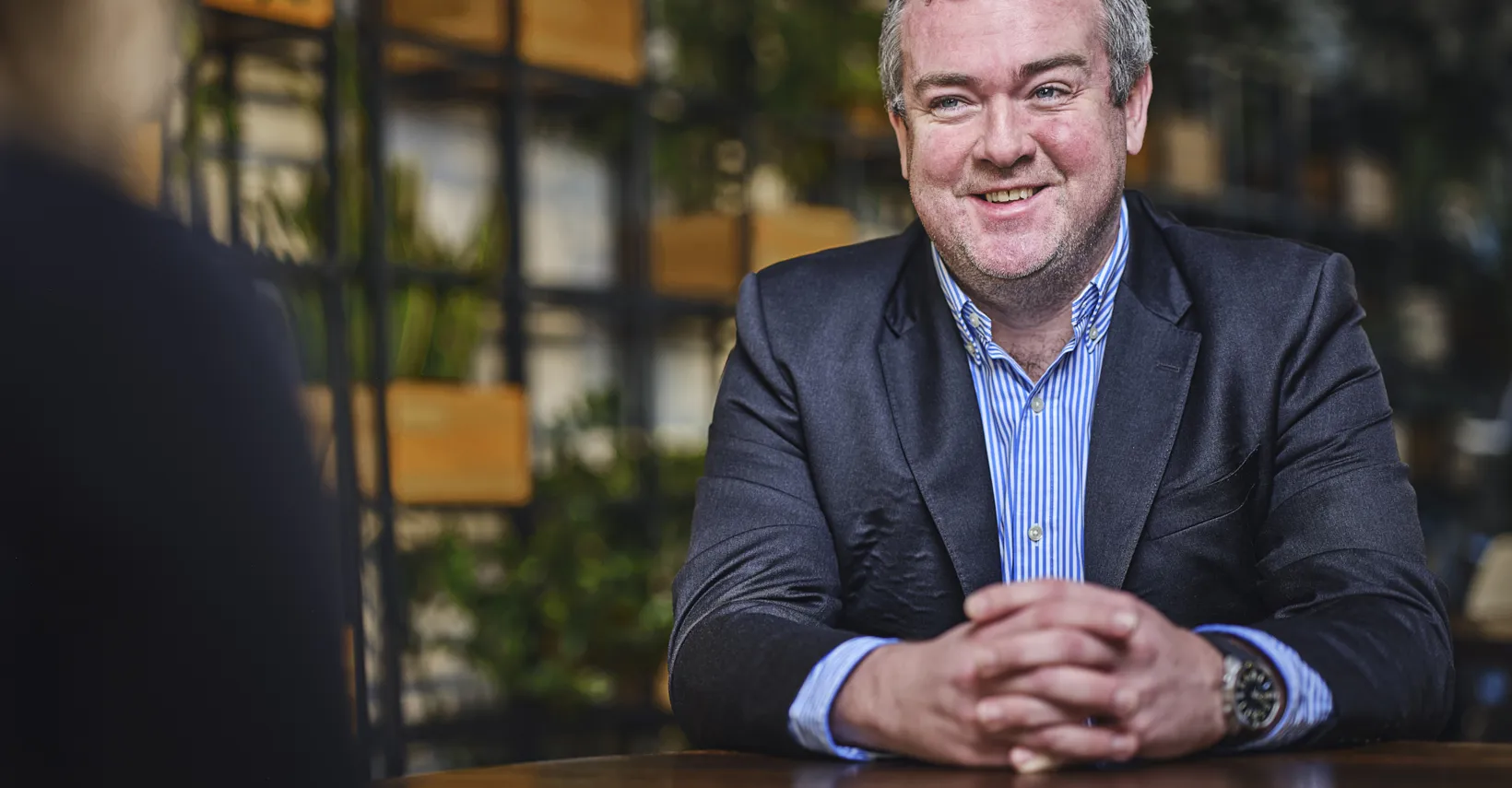 man talking and smiling at table, talking to someone