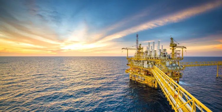Offshore oil rig at sunset over the ocean.