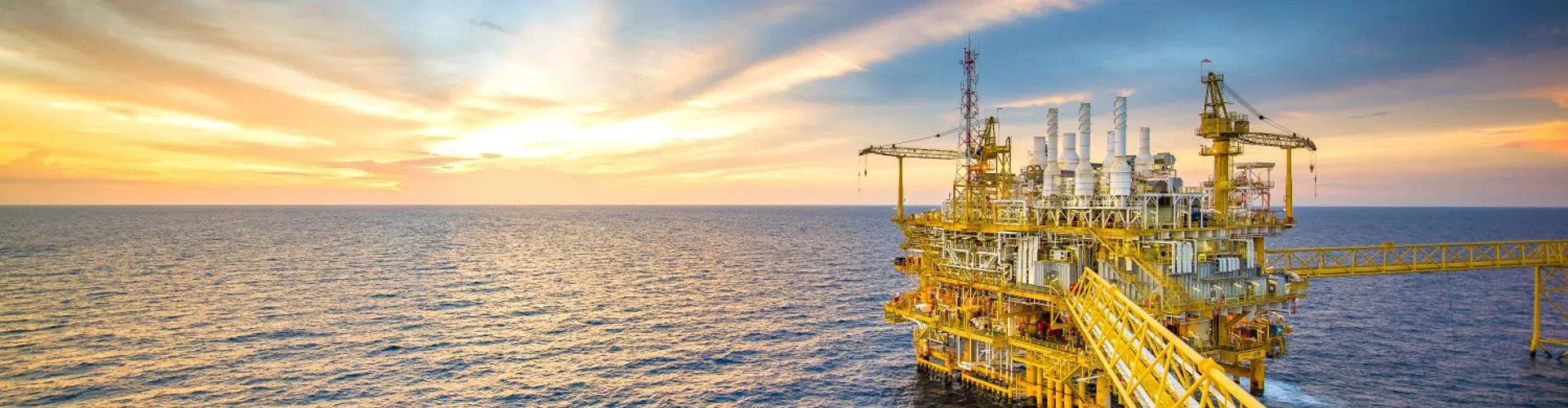 Offshore oil rig at sunset over the ocean.