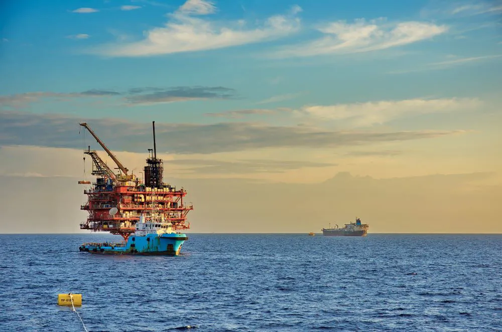 Offshore oil rig against a sunset backdrop.