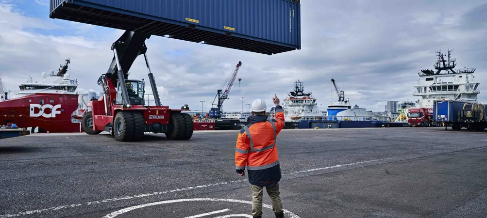 Worker signaling a crane lifting a shipping container.