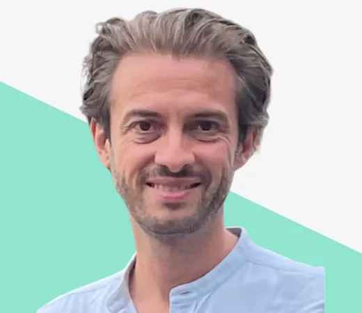 Smiling man with light hair in a blue shirt.