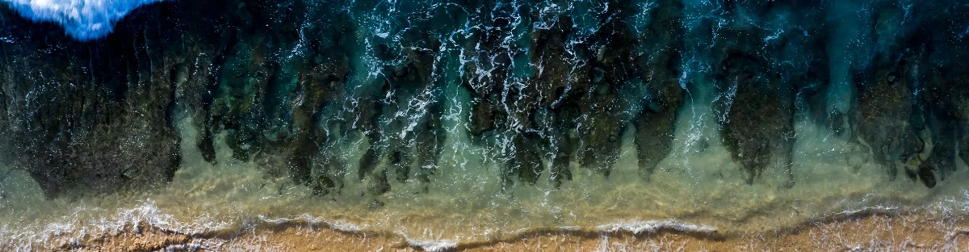 Aerial view of ocean waves meeting sandy beach.