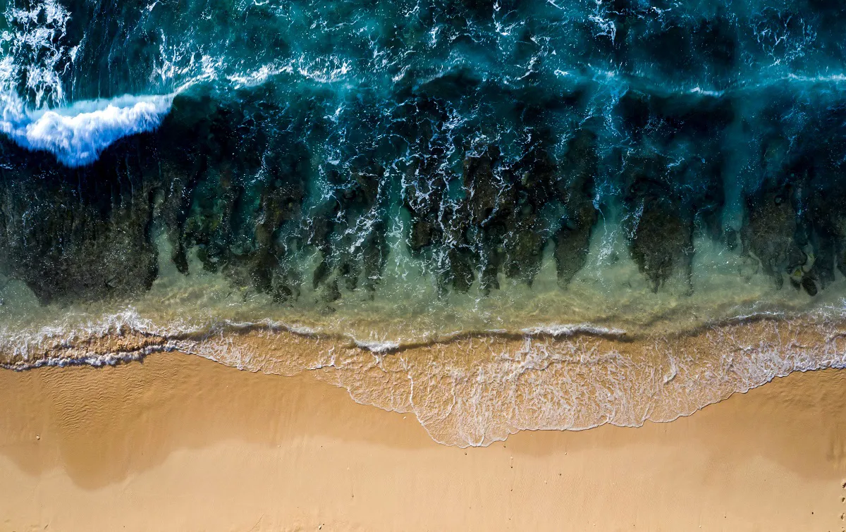 Aerial view of ocean waves meeting sandy beach.