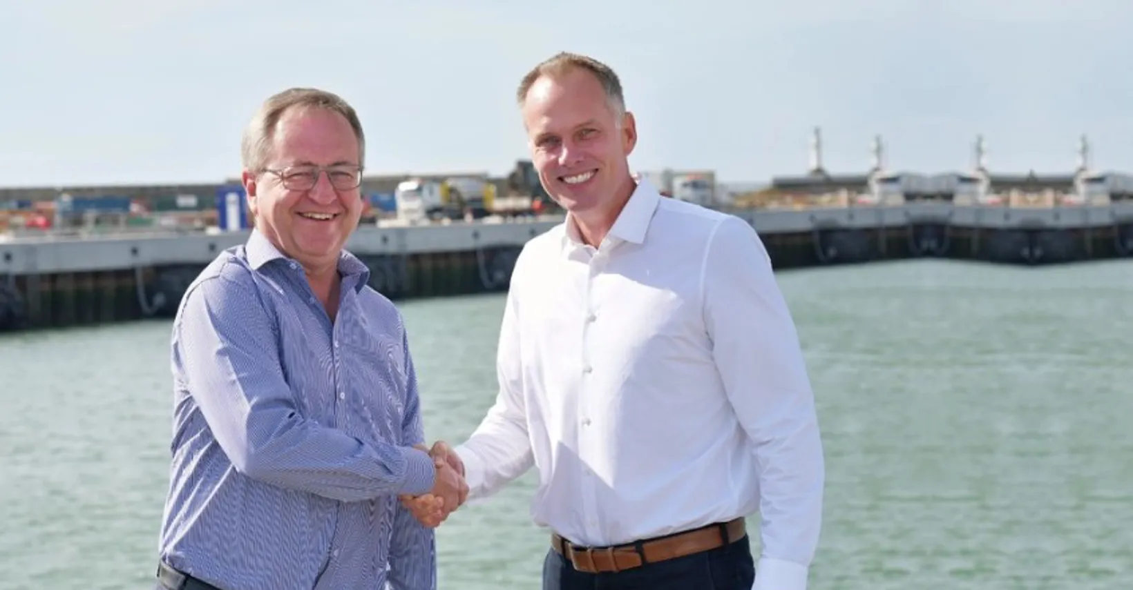 Two men shaking hands by the waterfront.