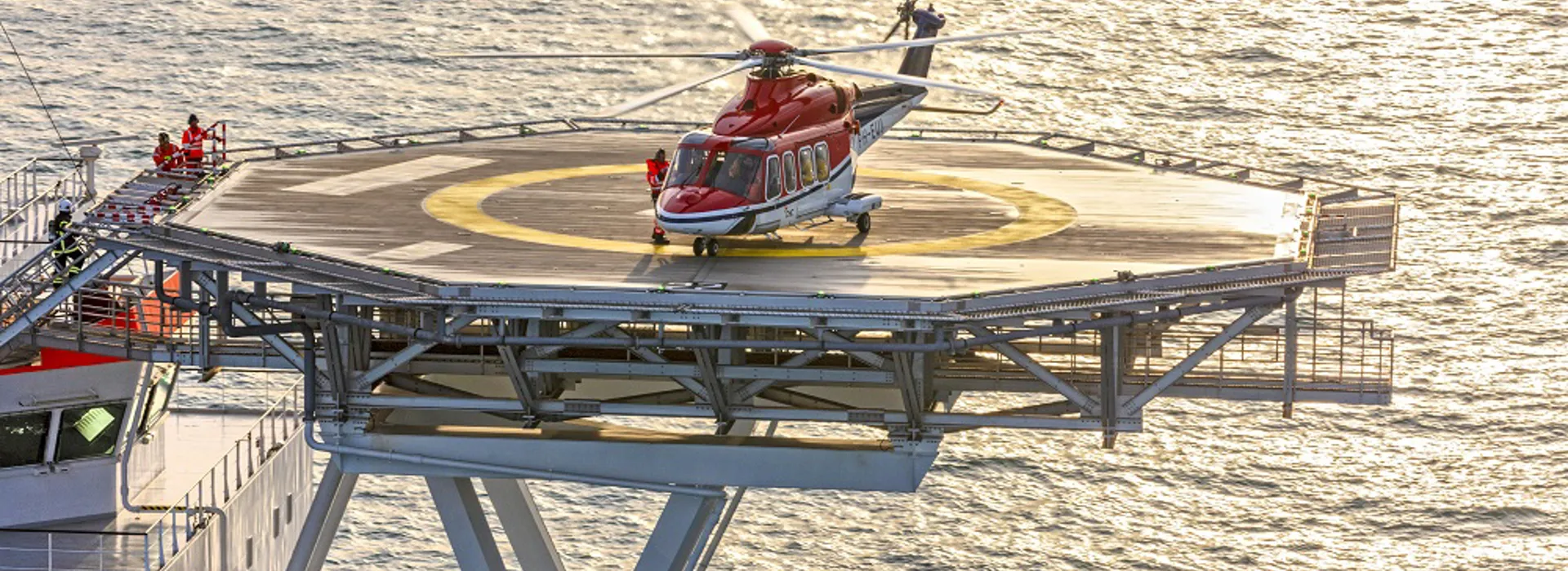 Helicopter on a helipad over the ocean.
