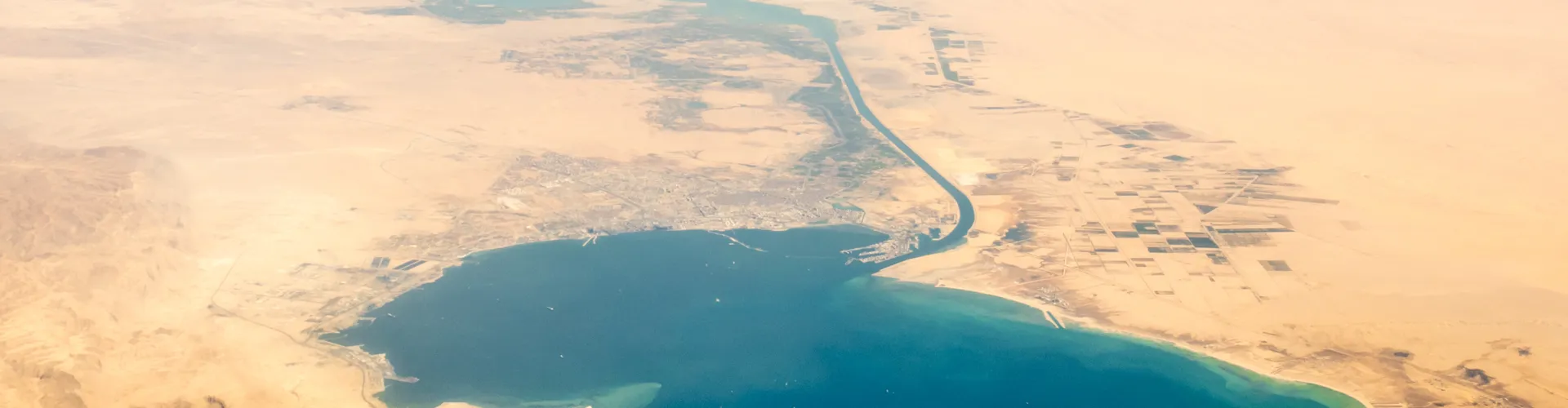 Aerial view of desert and blue water coastline.