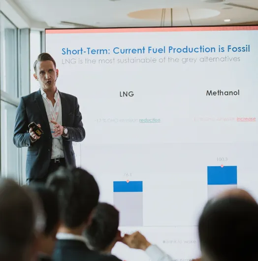 Presenter discusses fuel production with a chart.
