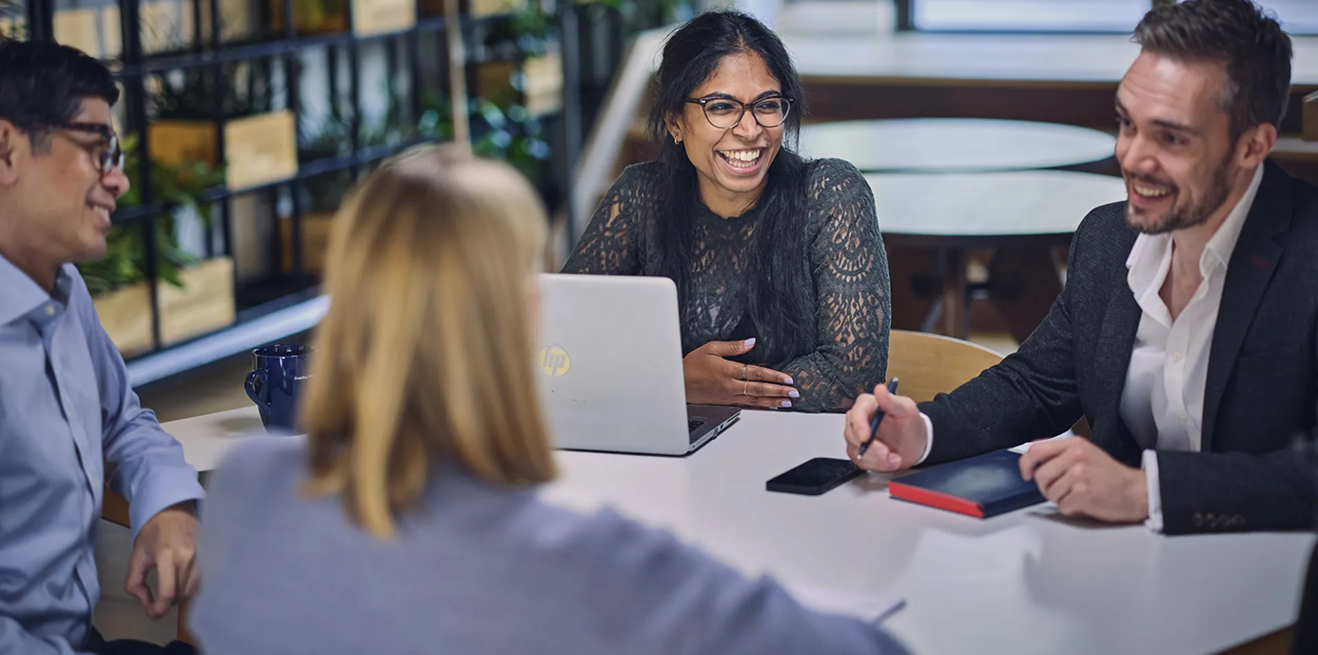 colleagues smiling and discussing work at a table