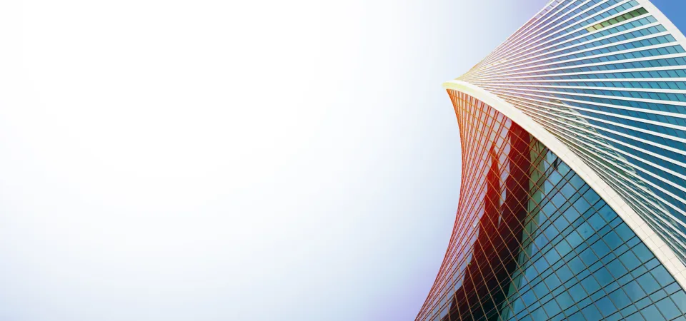 Curved modern skyscraper against a bright sky.