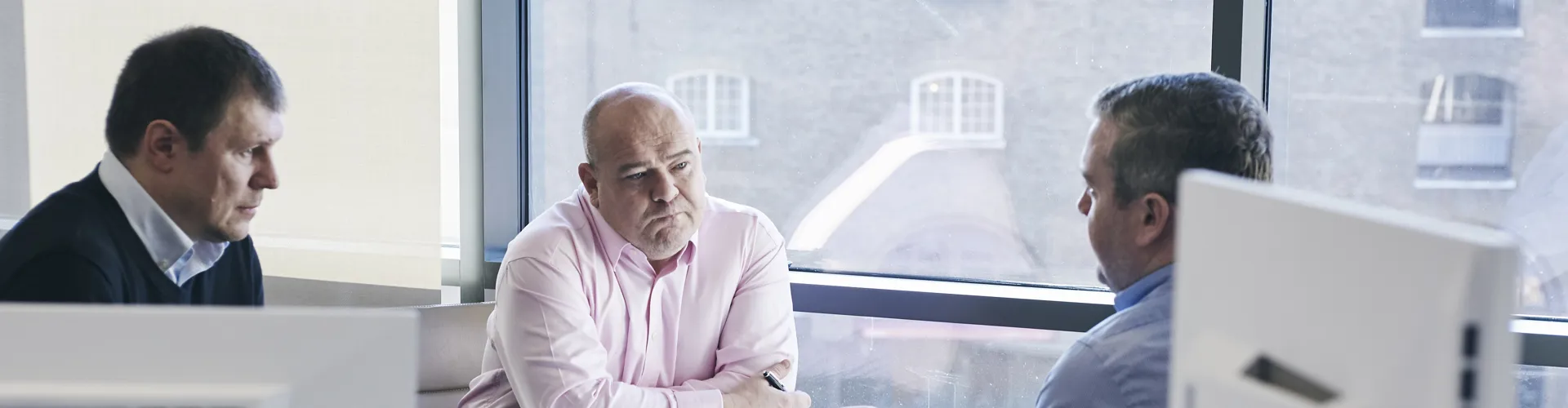 three men discussing work around a table
