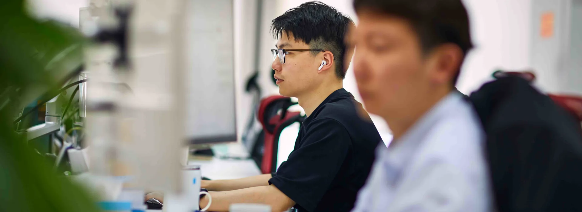 Two people working at desks in an office setting.