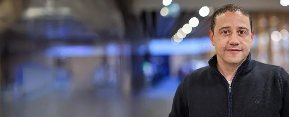 Man in a dark sweater standing in a hallway.