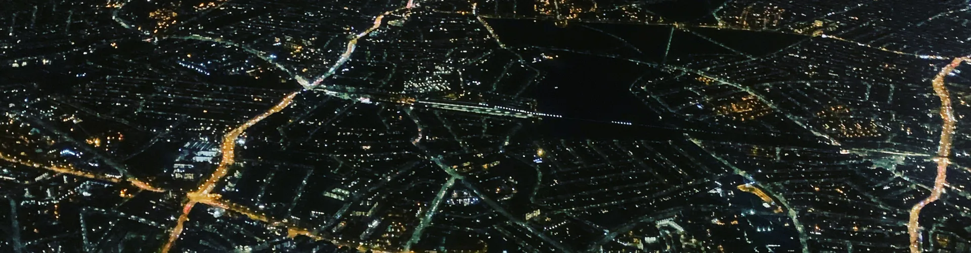 City lights illuminate streets at night from above.