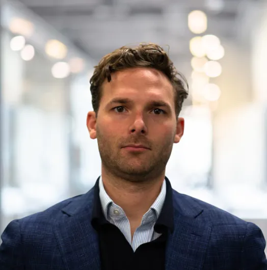 Man in a navy blazer facing the camera.
