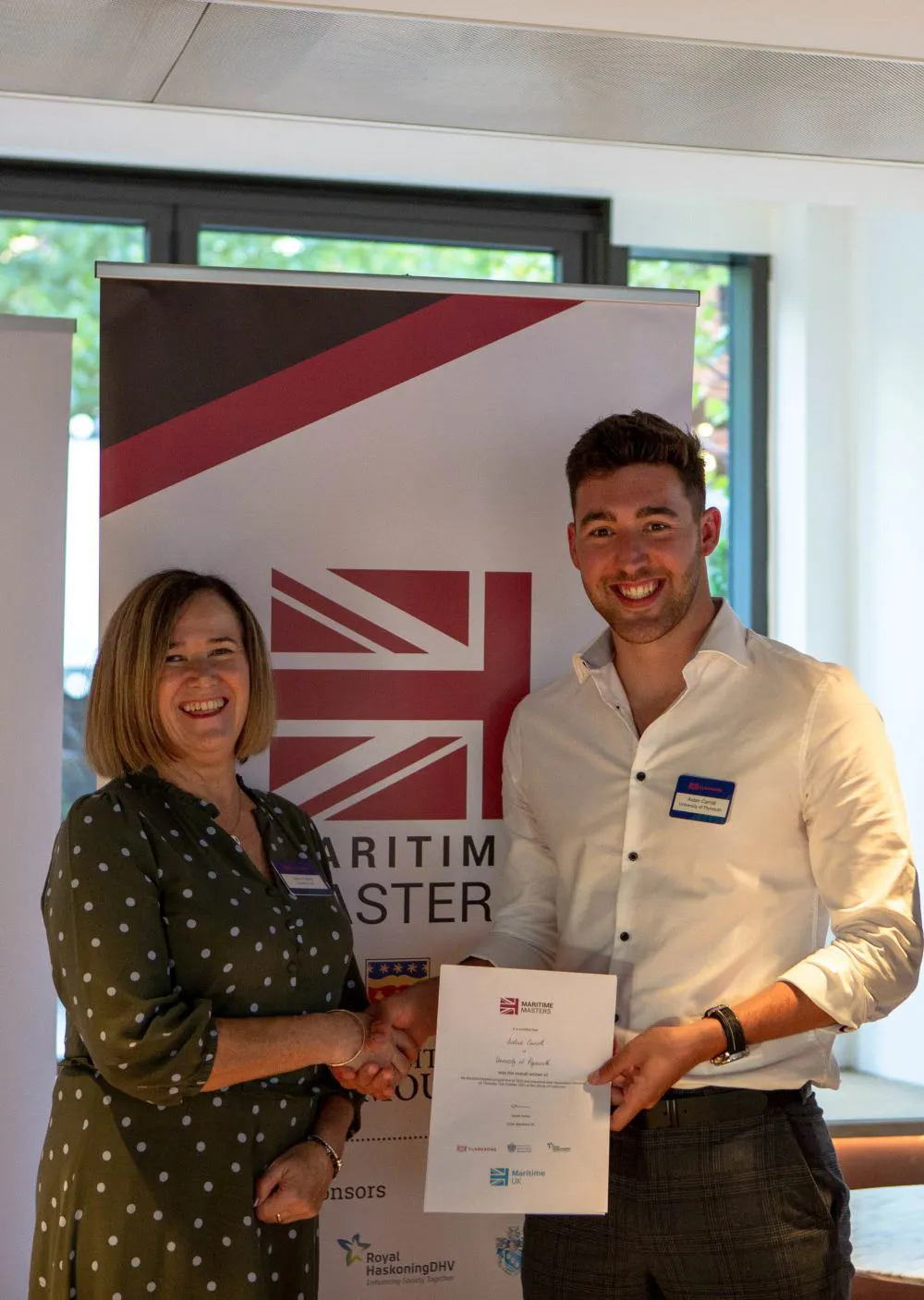 Two people shaking hands with a certificate.