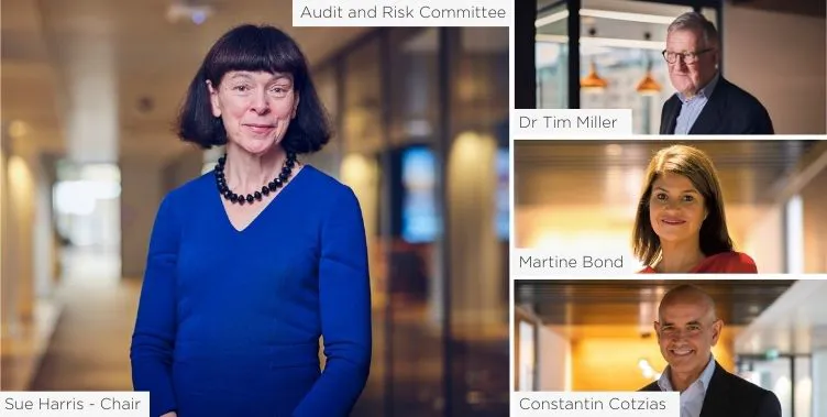 A woman in a blue dress stands smiling.